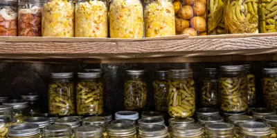 Jars of vegetables arranged in rows on two pantry shelves.