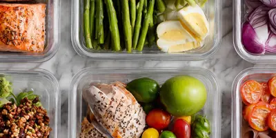 Six clear containers filled with prepared vegetables, chicken, and eggs. 