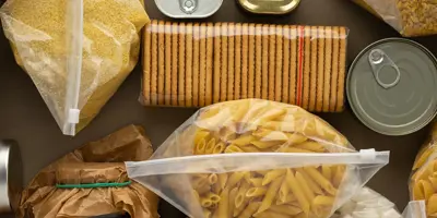 Cans and bags of food arranged on a table, displaying shelf-stable food items like pasta and marshmallows.