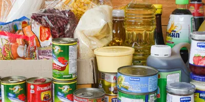 Cans and bottles of food arranged on a wooden table.
